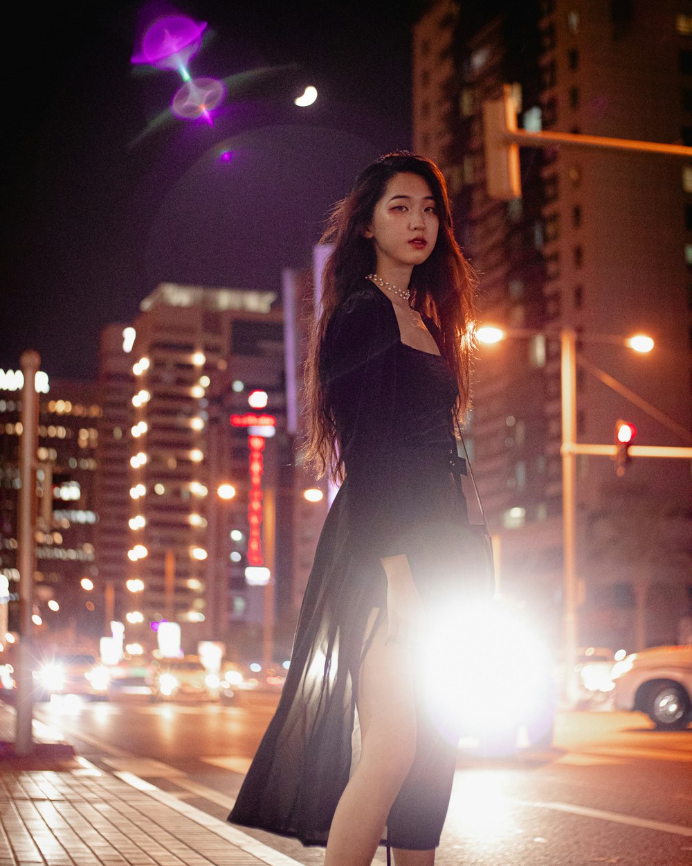 woman in black dress standing on street during night time