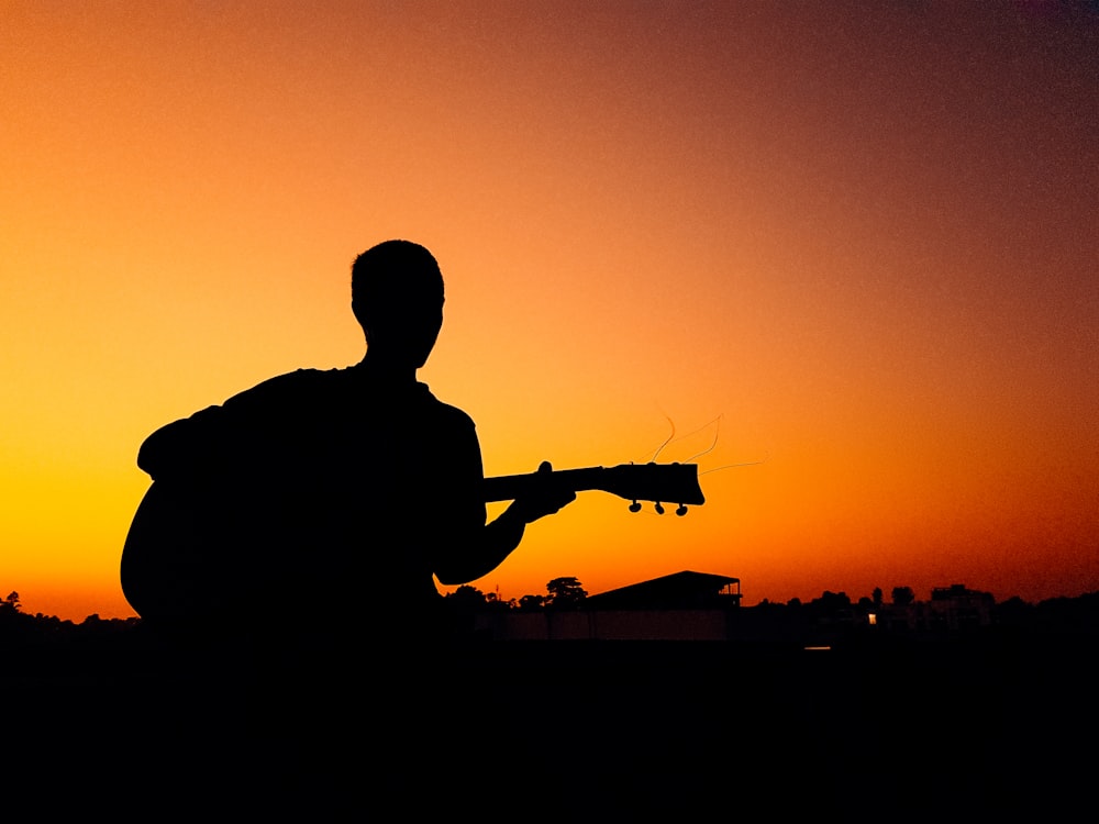 silhouette of man holding camera during sunset