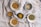 A collection of various spices displayed in small bowls on a textured cloth background. The spices range in colors and textures, including crushed seeds, dried herbs, and finely ground powders. The arrangement creates a natural and rustic culinary setting.