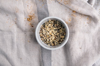 A rustic bowl filled with a colorful assortment of raw nuts and seeds on a beige linen cloth.