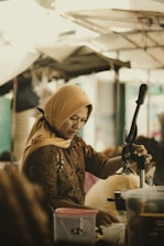 woman in brown hijab holding black smartphone
