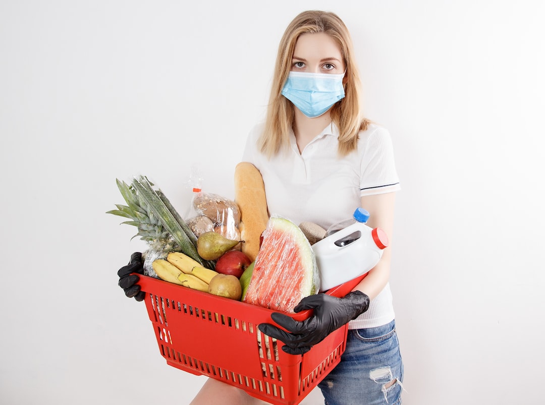 woman in white long sleeve shirt and blue denim jeans holding red plastic basket with fruits