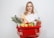 woman in white dress shirt holding red plastic basket with fruits