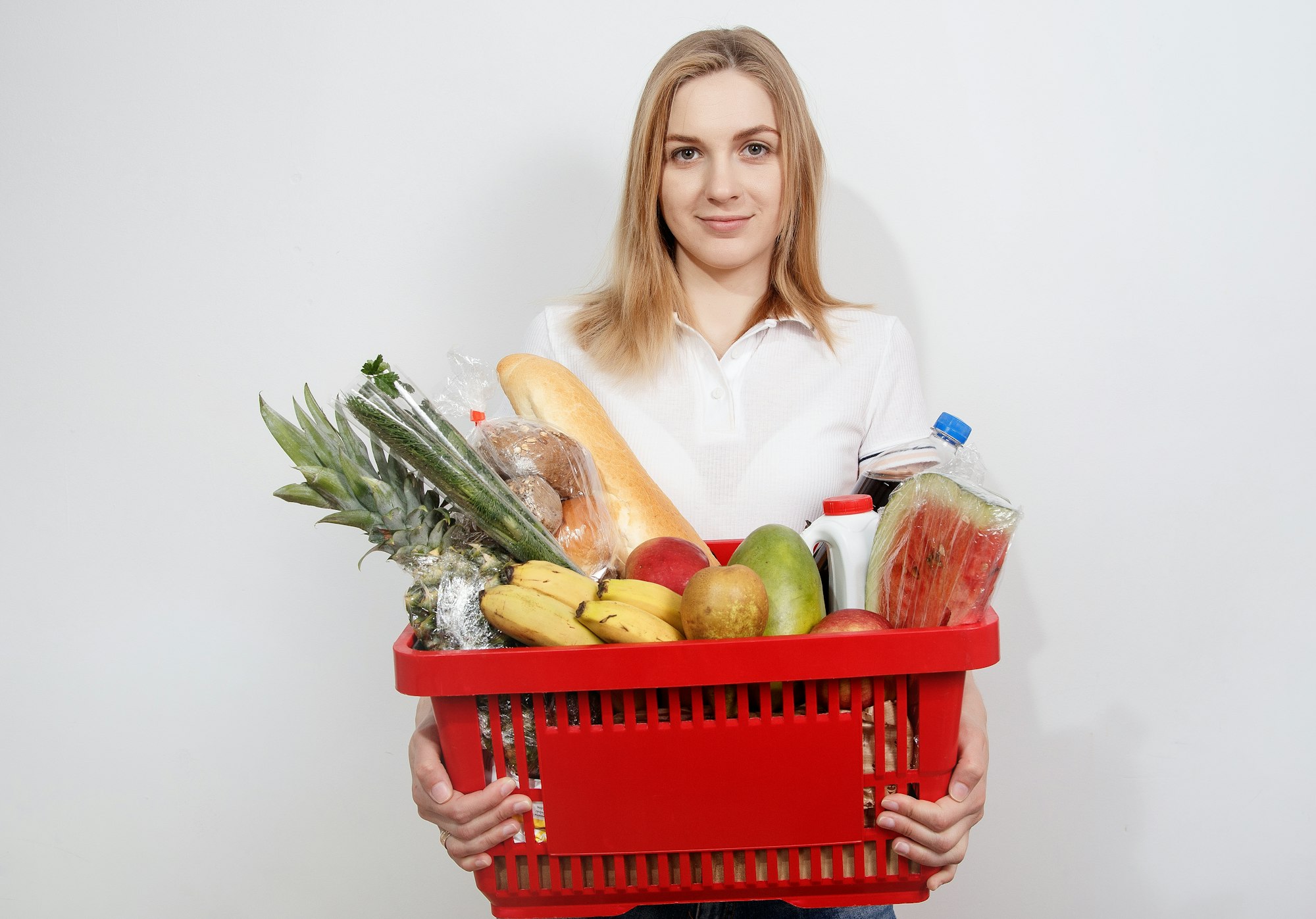Young woman with goods in basket. The girl made a purchase. Girl holding a basket of groceries. Vegetables
