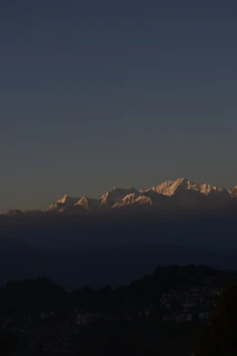 Snow-capped peaks glowing golden at sunset above a quiet mountain village.