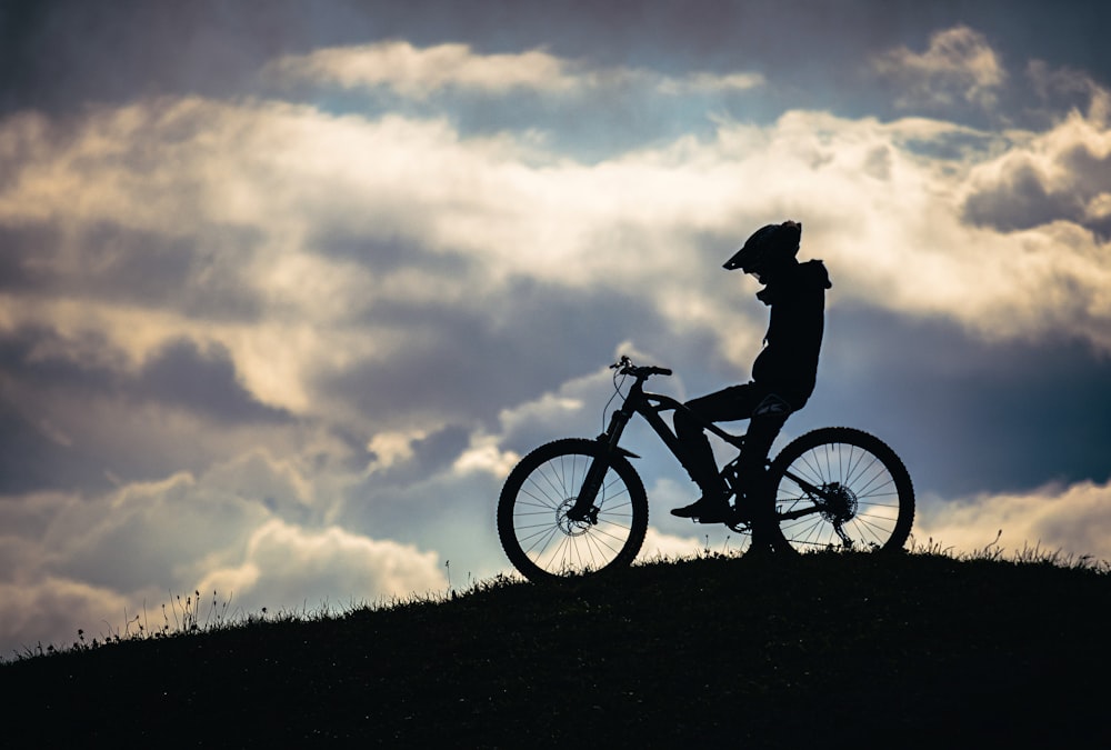 silhouette of person riding on bicycle during daytime