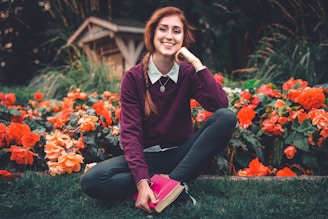 woman in red and black long sleeve shirt and black pants sitting on green grass field