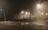 A foggy street scene with weathered church silhouette and glowing lanterns faintly visible through the mist.