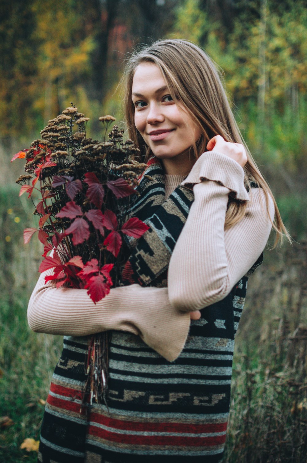 woman in brown scarf standing beside red flowers