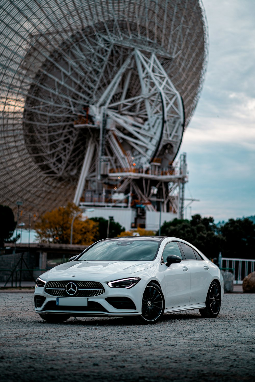 Mercedes Benz coupé bianca parcheggiata vicino alla ruota panoramica durante il giorno