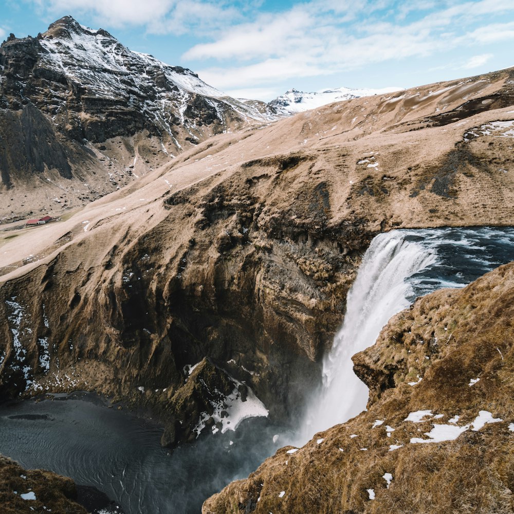 montagnes brunes et blanches près d’un plan d’eau pendant la journée