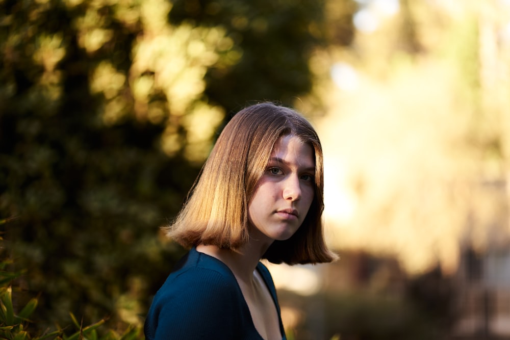 Femme en chemise bleue debout près de l’herbe verte pendant la journée