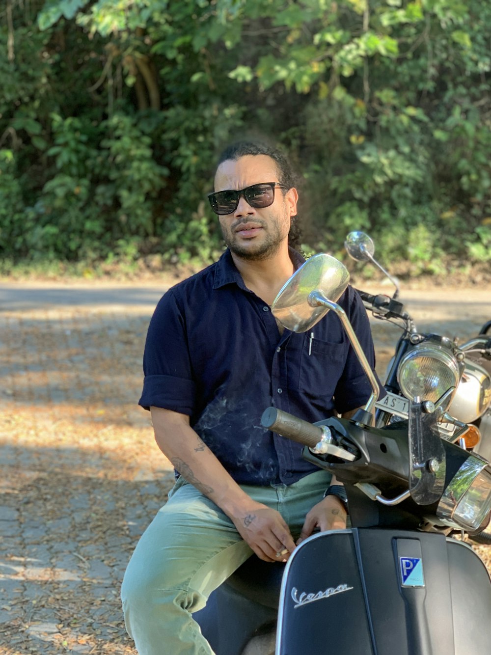 man in blue dress shirt and green shorts sitting on motorcycle