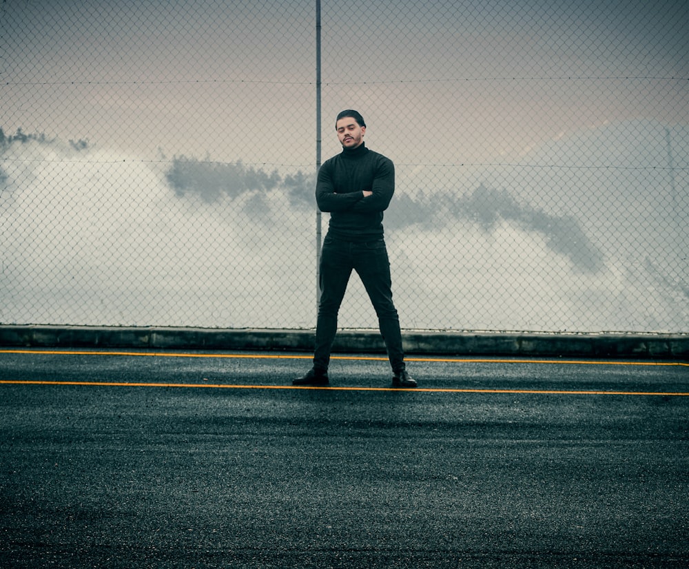 man in black jacket standing on gray asphalt road during daytime