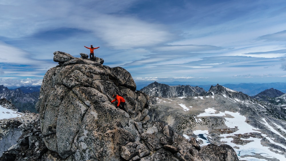 person in red jacket sitting on rock formation during daytime