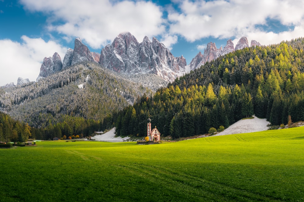 green grass field near mountain under blue sky during daytime