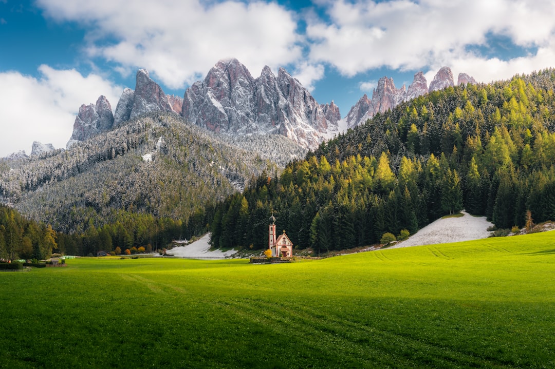 green grass field near mountain under blue sky during daytime