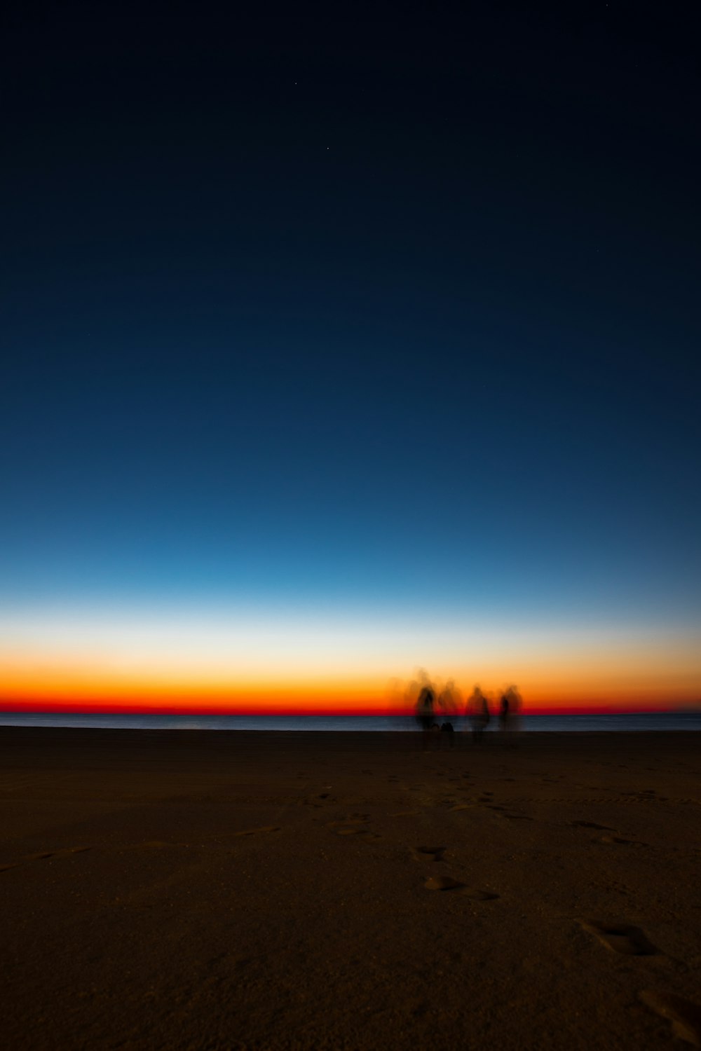 silhouette of 2 people walking on beach during sunset