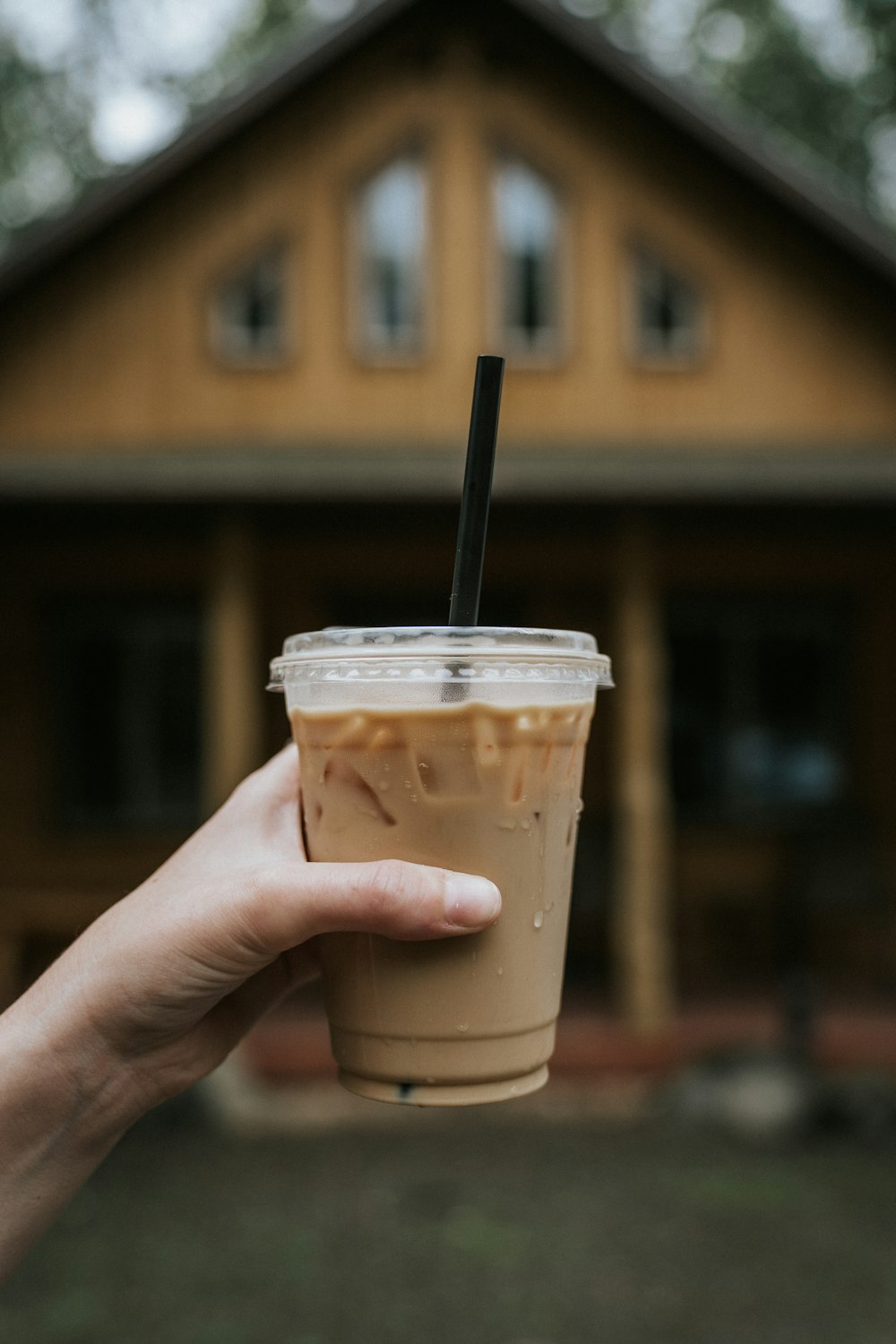 person holding white plastic cup with black straw