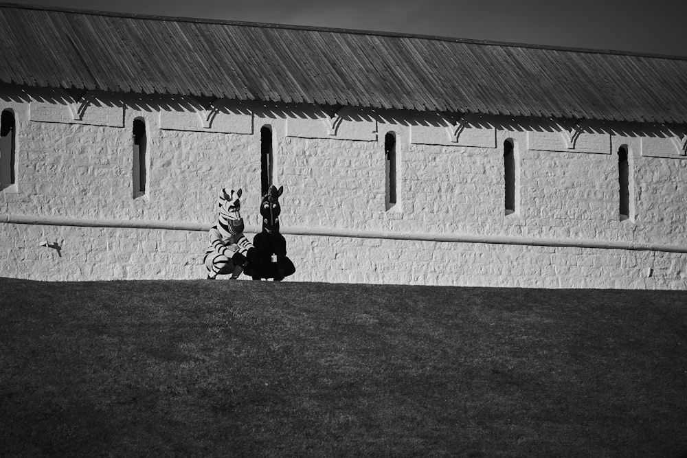 grayscale photo of man sitting on grass field