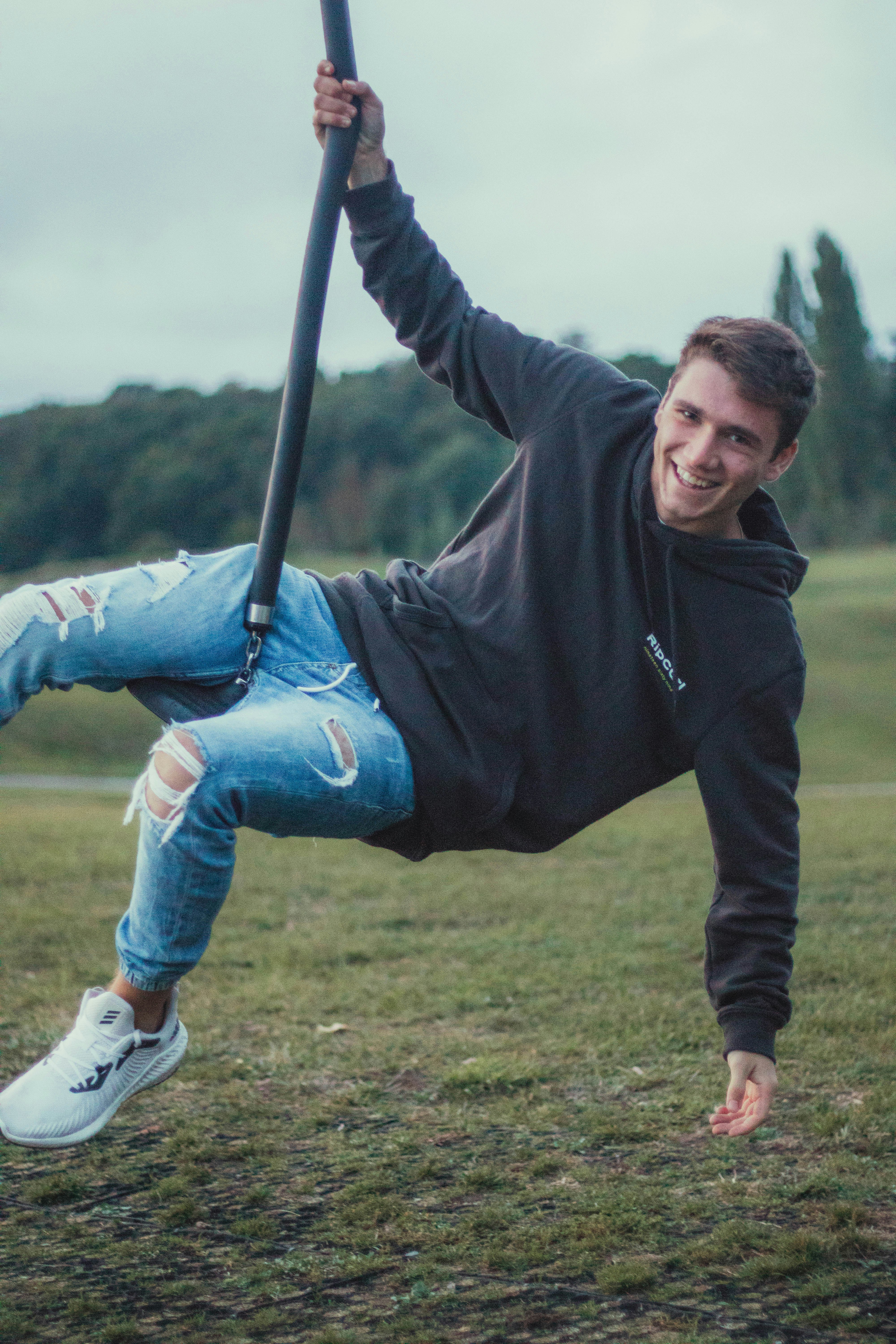 woman in black sweater and blue denim jeans sitting on swing during daytime