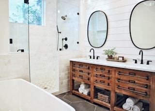 white ceramic bathtub near brown wooden cabinet