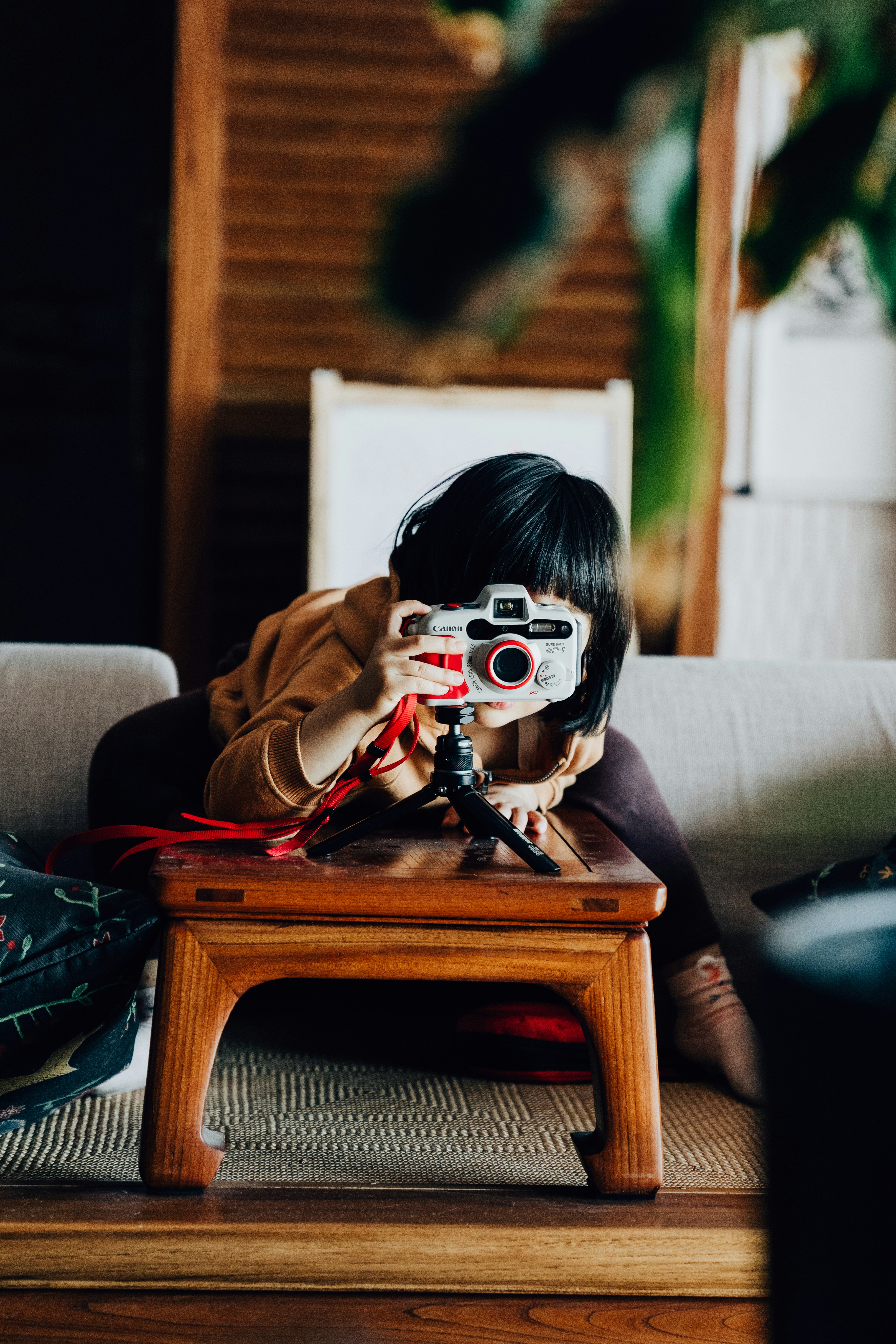 woman in brown coat holding black camera