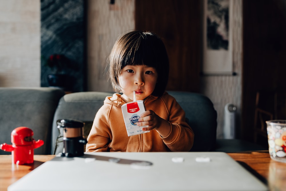 girl in brown hoodie holding white and red ceramic mug