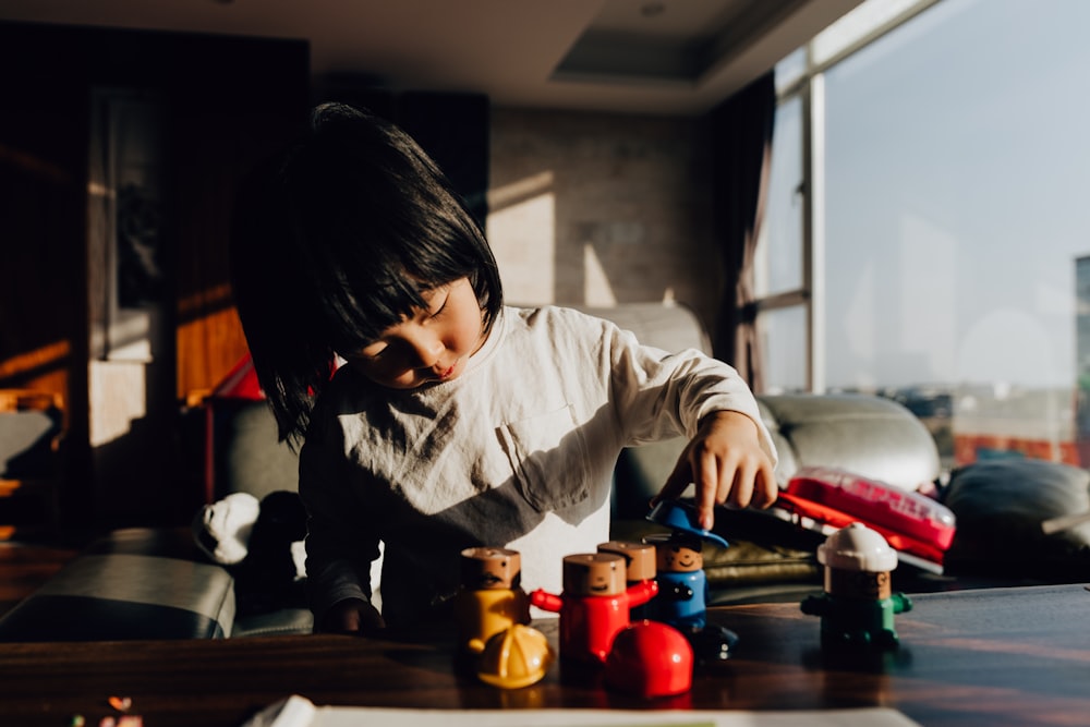 boy in white long sleeve shirt sitting on brown wooden table