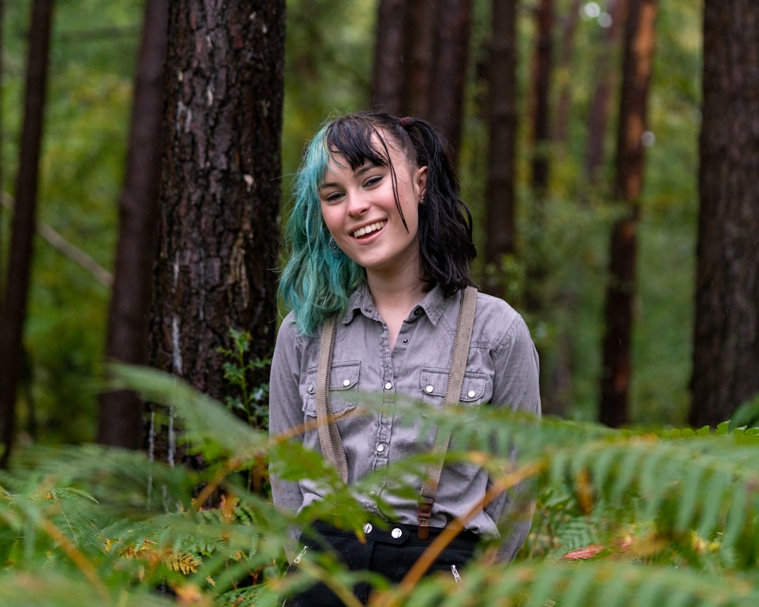 woman in gray button up shirt holding green plant