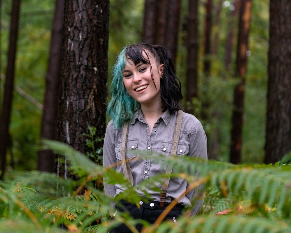 donna in camicia grigia abbottonata che tiene la pianta verde