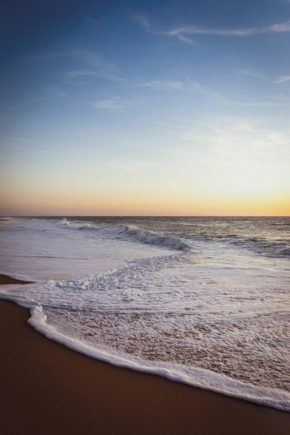 olas del mar rompiendo en la costa durante la puesta de sol