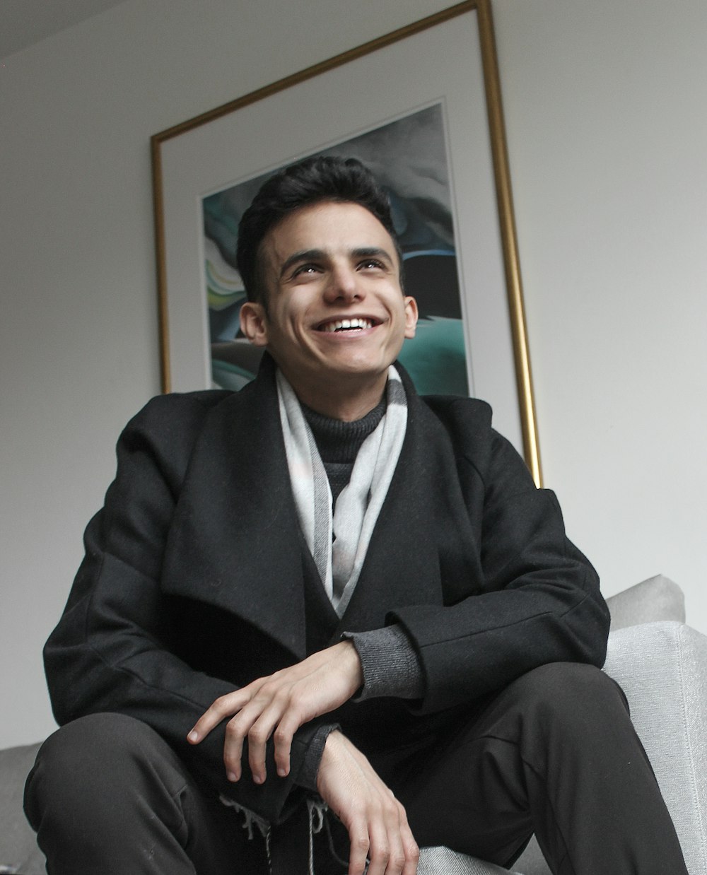 man in black suit jacket sitting on white sofa