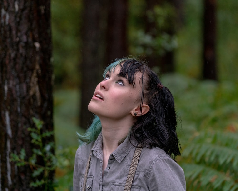 woman in gray denim jacket standing near tree during daytime