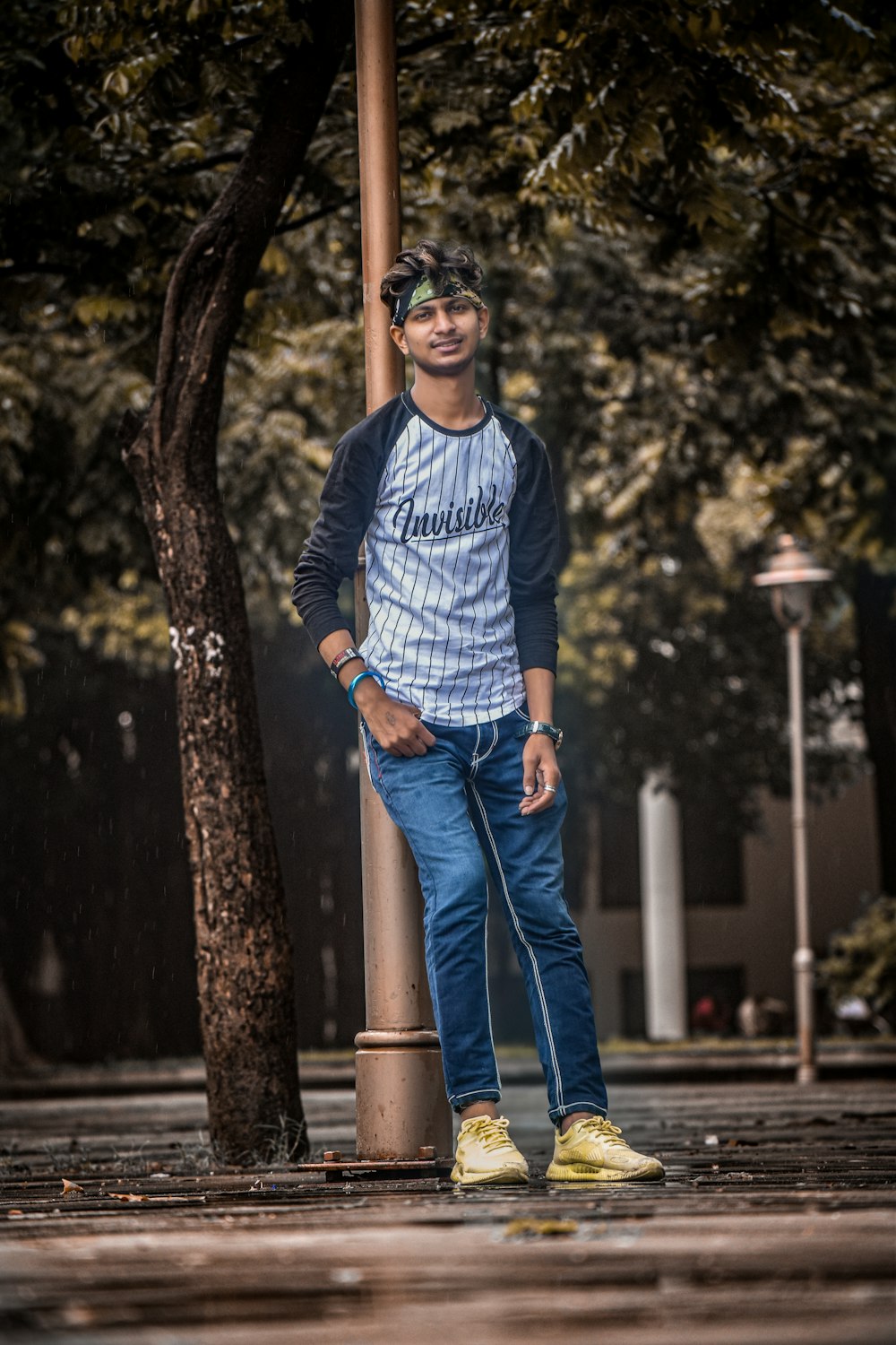 man in blue and white striped sweater and blue denim jeans standing beside tree during daytime