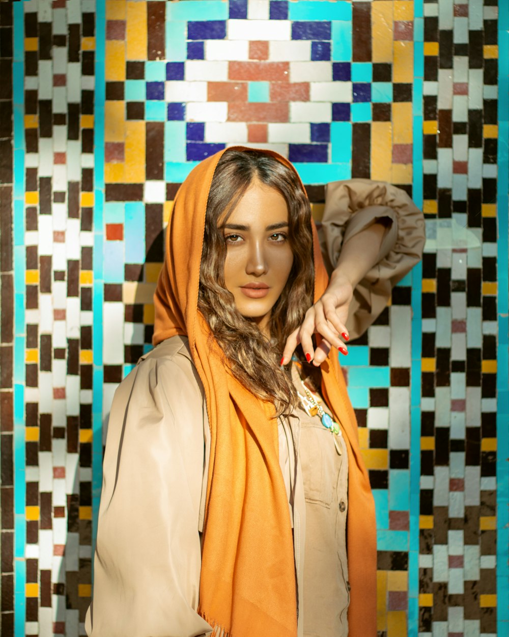 woman in beige coat standing beside blue white and yellow wall