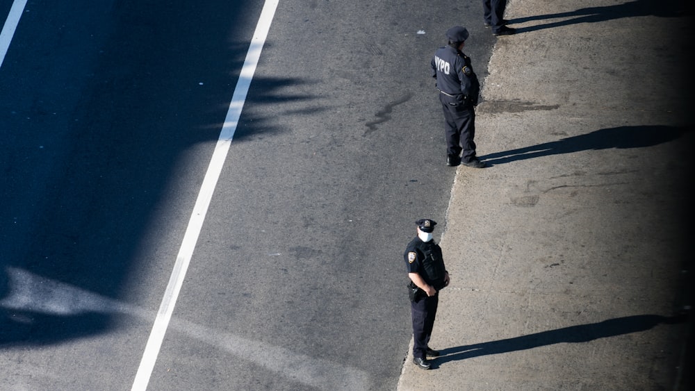 man in black shirt walking on gray asphalt road during daytime