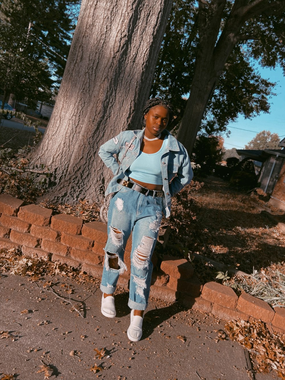 girl in white and blue denim jacket and blue denim jeans standing near brown tree during