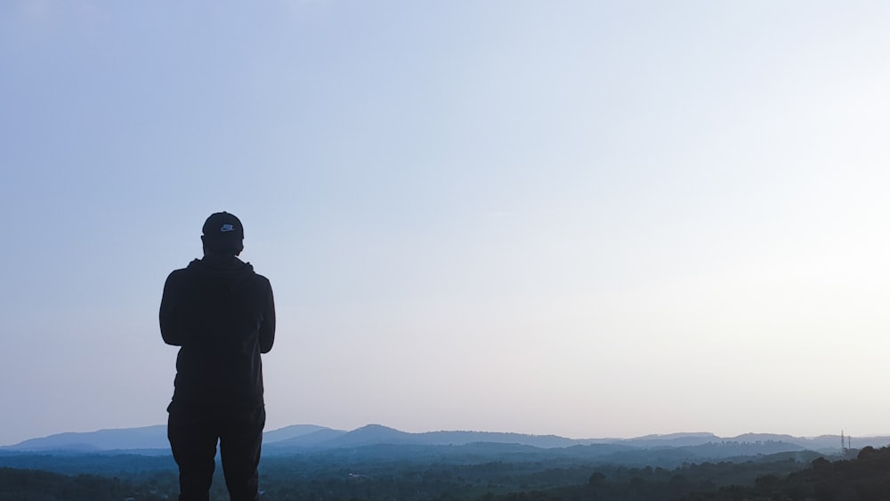 man in black jacket standing on top of mountain during daytime