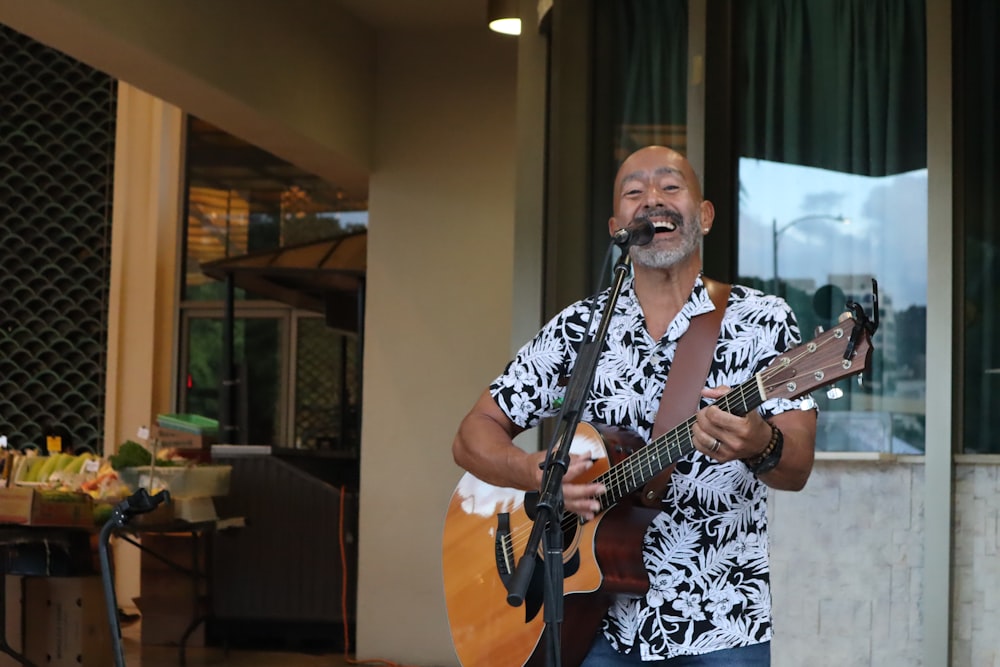 homem na camisa floral preta e branca que joga guitarra