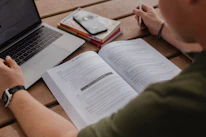 person in green long sleeve shirt sitting beside macbook pro