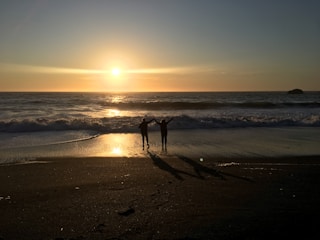 Golden hour shot of a couple holding hands near the seaside.