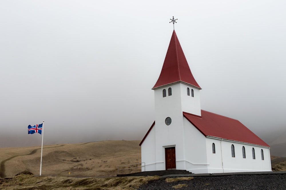 낮에는 하얀 하늘 아래 갈색 들판에 있는 흰색과 빨간색 교회