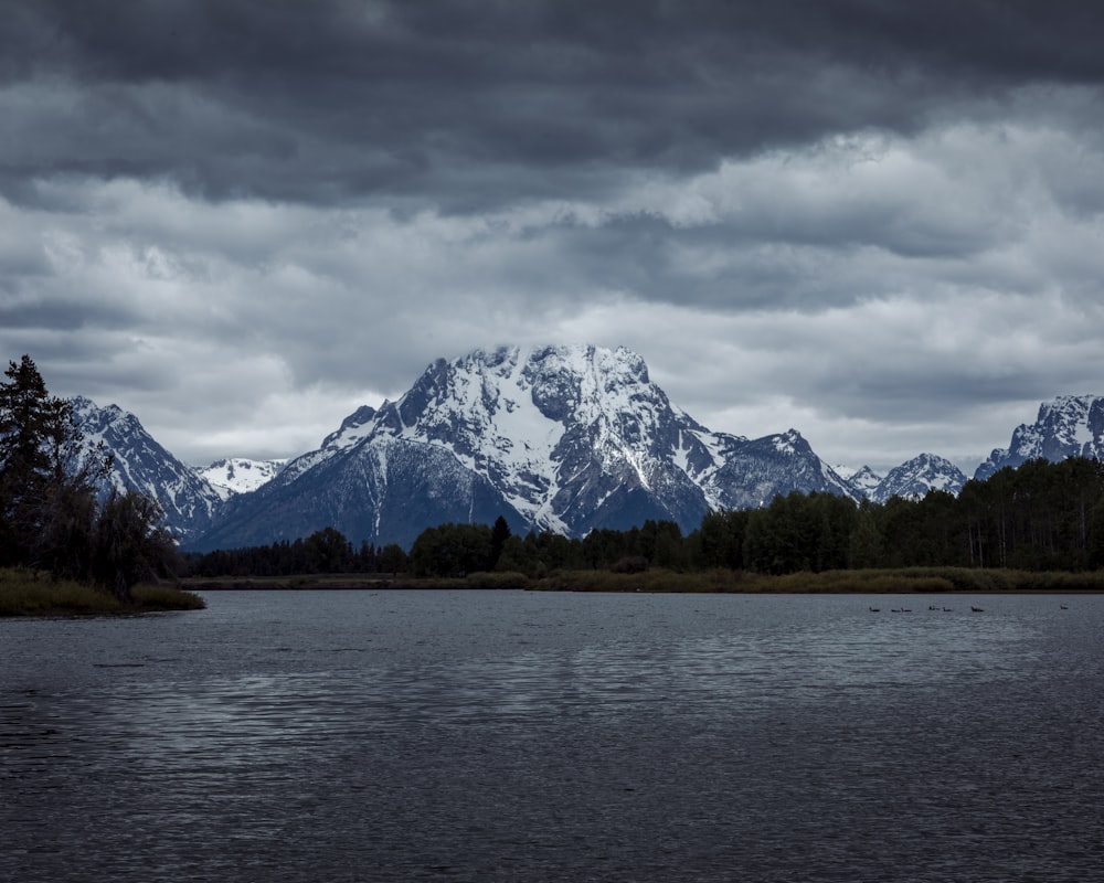 snow covered mountain near body of water during daytime