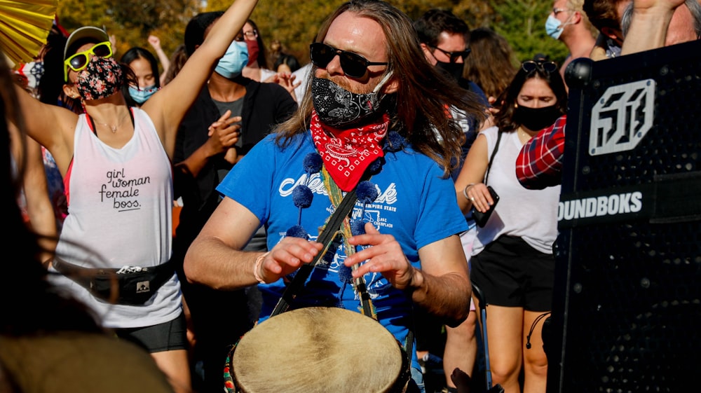 woman in blue crew neck t-shirt wearing red mask holding drum stick