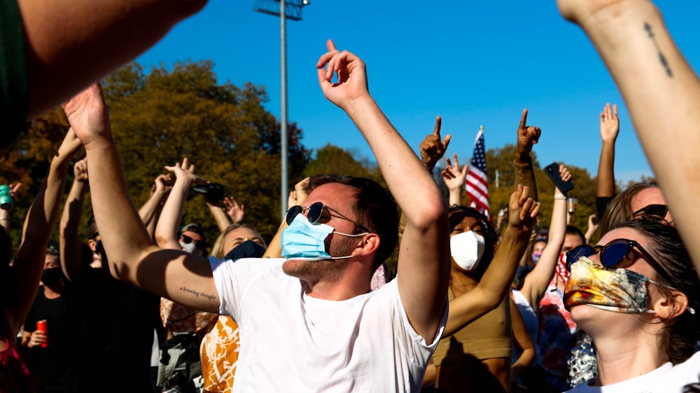 man in white crew neck t-shirt wearing sunglasses raising his right hand