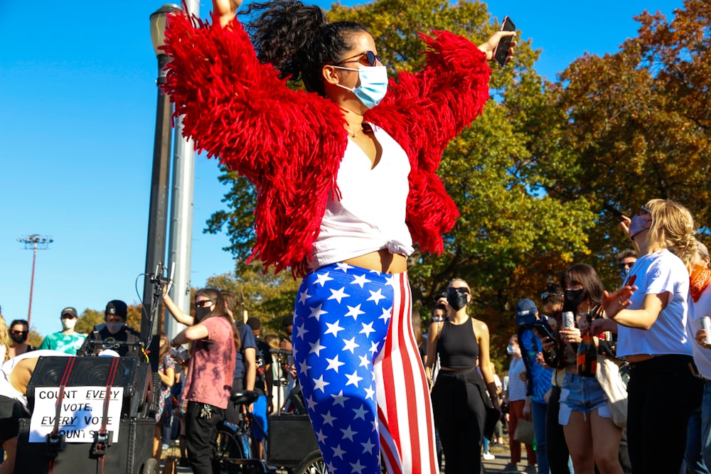 woman in red long sleeve shirt and blue white and red pants standing near people during