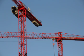 red and white crane under blue sky during daytime