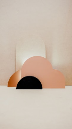 Geometric shapes composed of pastel-colored semi-circles and arches are arranged artistically against a neutral background, creating a minimalist aesthetic.