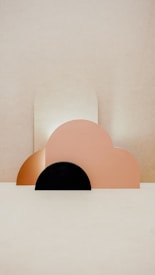 Geometric shapes composed of pastel-colored semi-circles and arches are arranged artistically against a neutral background, creating a minimalist aesthetic.